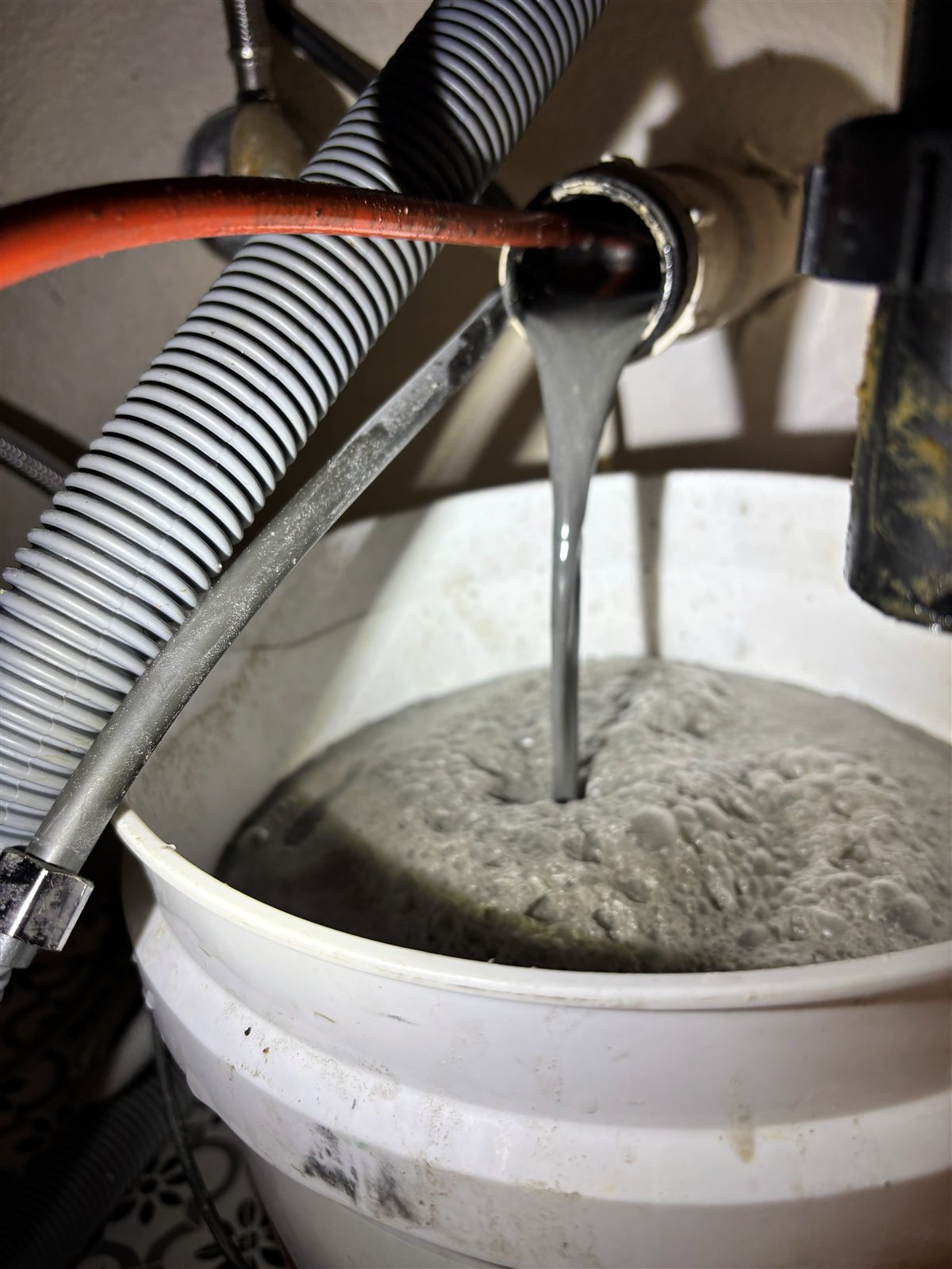 Water and drain buildup being flushed into a bucket during service